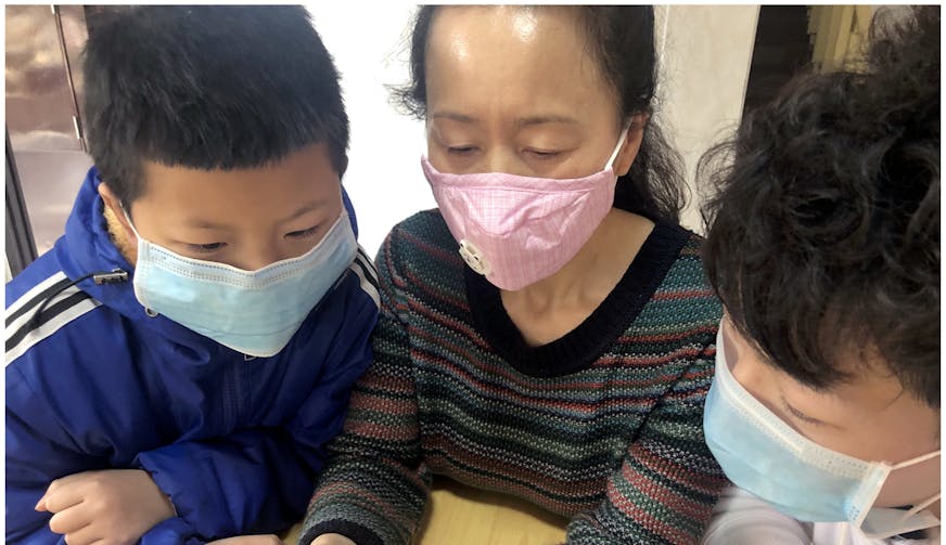 SOS moeder leest met kinderen instructies over voorkomen van besmetting met Corona virus - SOS Kinderdorpen