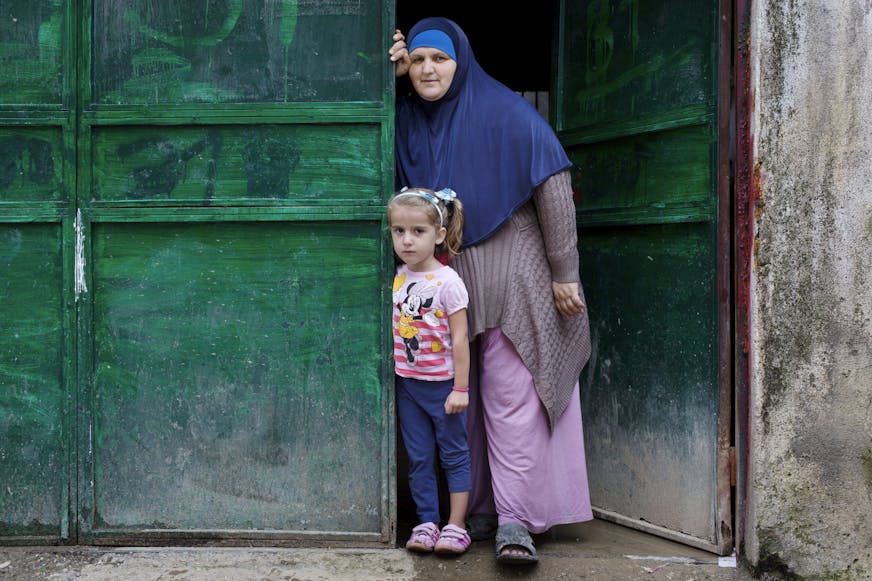 Zahra uit Kosovo met haar moeder bij een groene deur