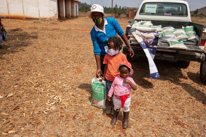 DRA Zimbabwe JR_vrouw haalt voedselpakket op met haar kinderen