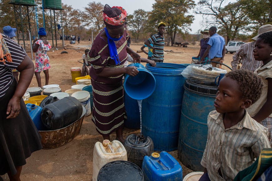 DRA Zimbabwe JR vrouw tapt water bij de herstelde waterbron