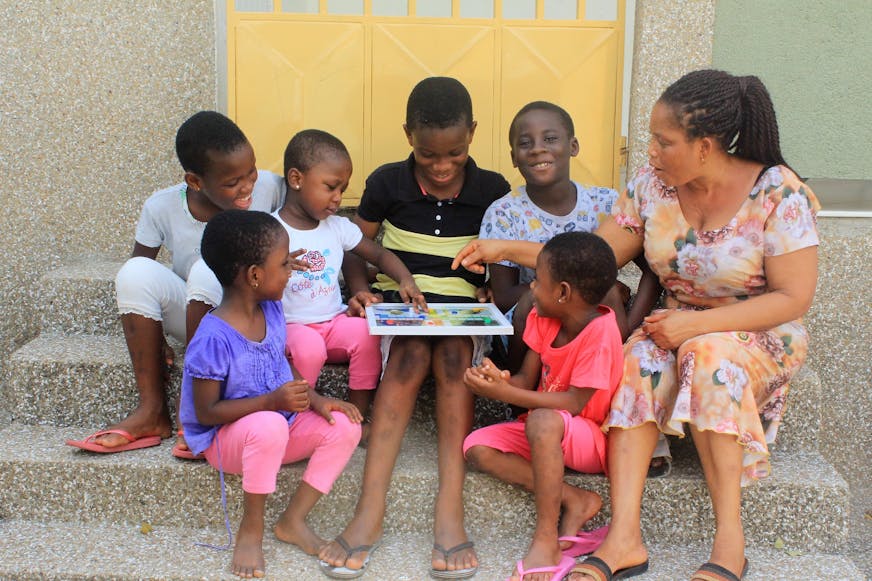 Ghana Asiakwa SOS moeder Agnes en haar kinderen op de stoep van hun familiehuis in de gemeenschap