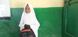 Jong meisje met hoofddoek houdt schooltas in haar hand