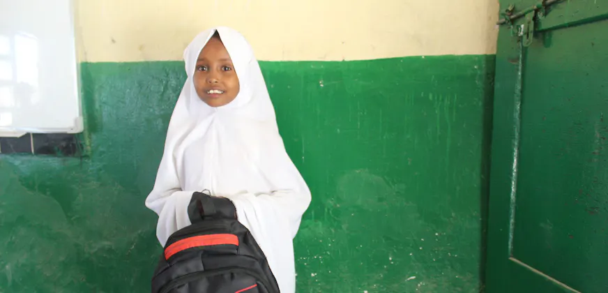 Jong meisje met hoofddoek houdt schooltas in haar hand