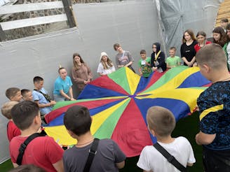 Kinderen op zomerkamp in Oekraïne 2024, ze houden een grote kleurrijke vlag vast.