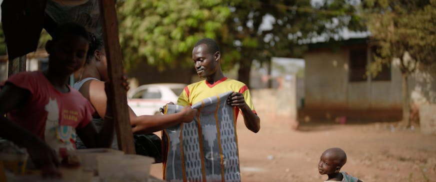 Koffi verkoopt zijn doeken op straat