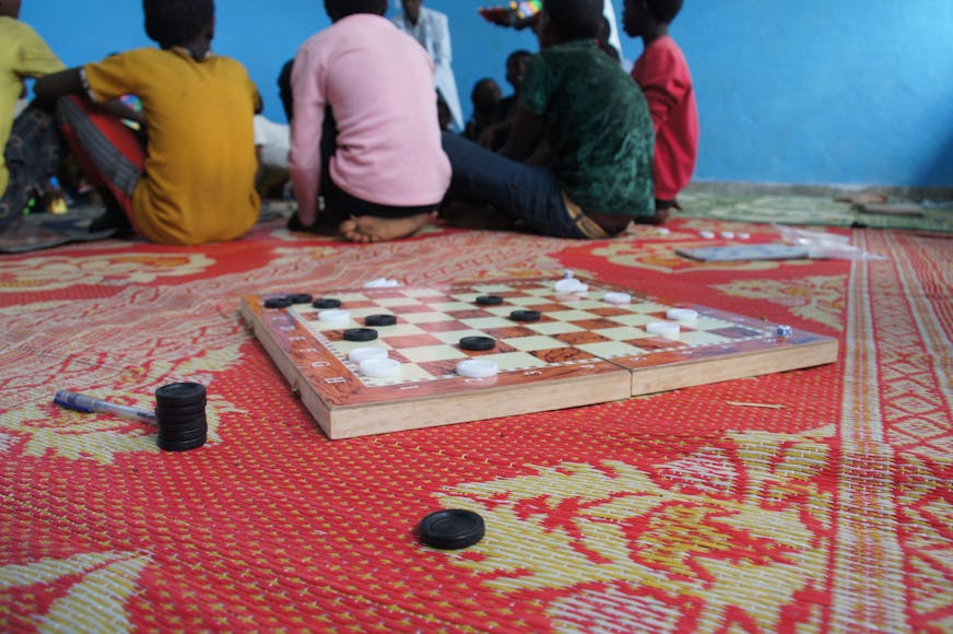 Dam bord en kinderen zitten op de grond in een kindvriendelijke ruimte