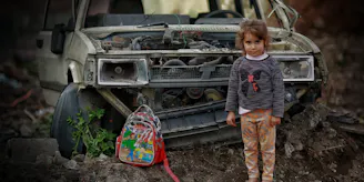 Meisje in Gaza voor uitgebrande auto