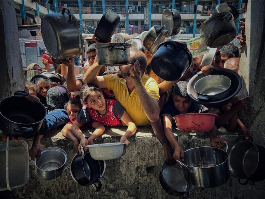 Kinderen en volwassenen in Gaza vragen om eten met pannen in hun handen.