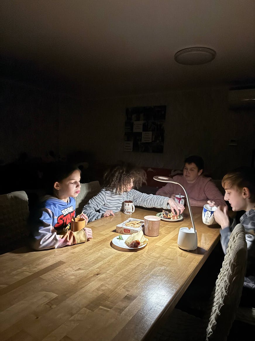 Kinderen die bij lampen op batterijen hun huiswerk maken tijdens stroomuitval.