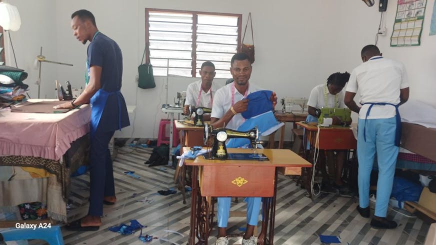 Wisdom werkt aan zijn kleding in het atelier