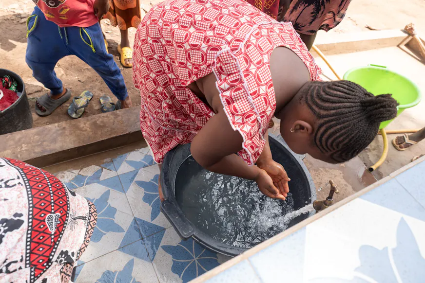 Dorpsbewoners halen schoon water bij het nieuwe waterpunt naast het gezondheidscentrum in Pelundo, Guinee-Bissau.