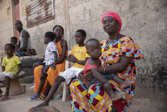 Een gezin uit Guinee-Bissau poseert samen buiten. Het gezin ontvangt ondersteuning van SOS Kinderdorpen.