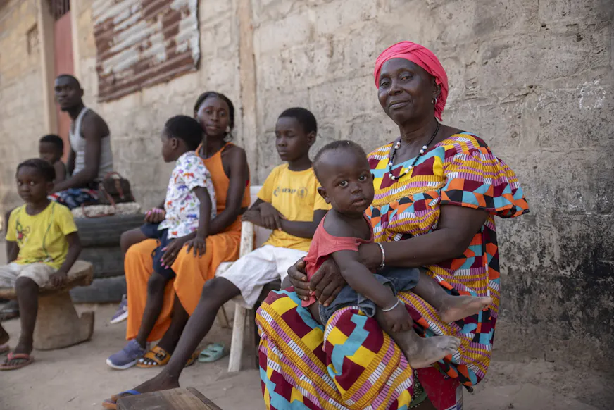 Een gezin uit Guinee-Bissau poseert samen buiten. Het gezin ontvangt ondersteuning van SOS Kinderdorpen.